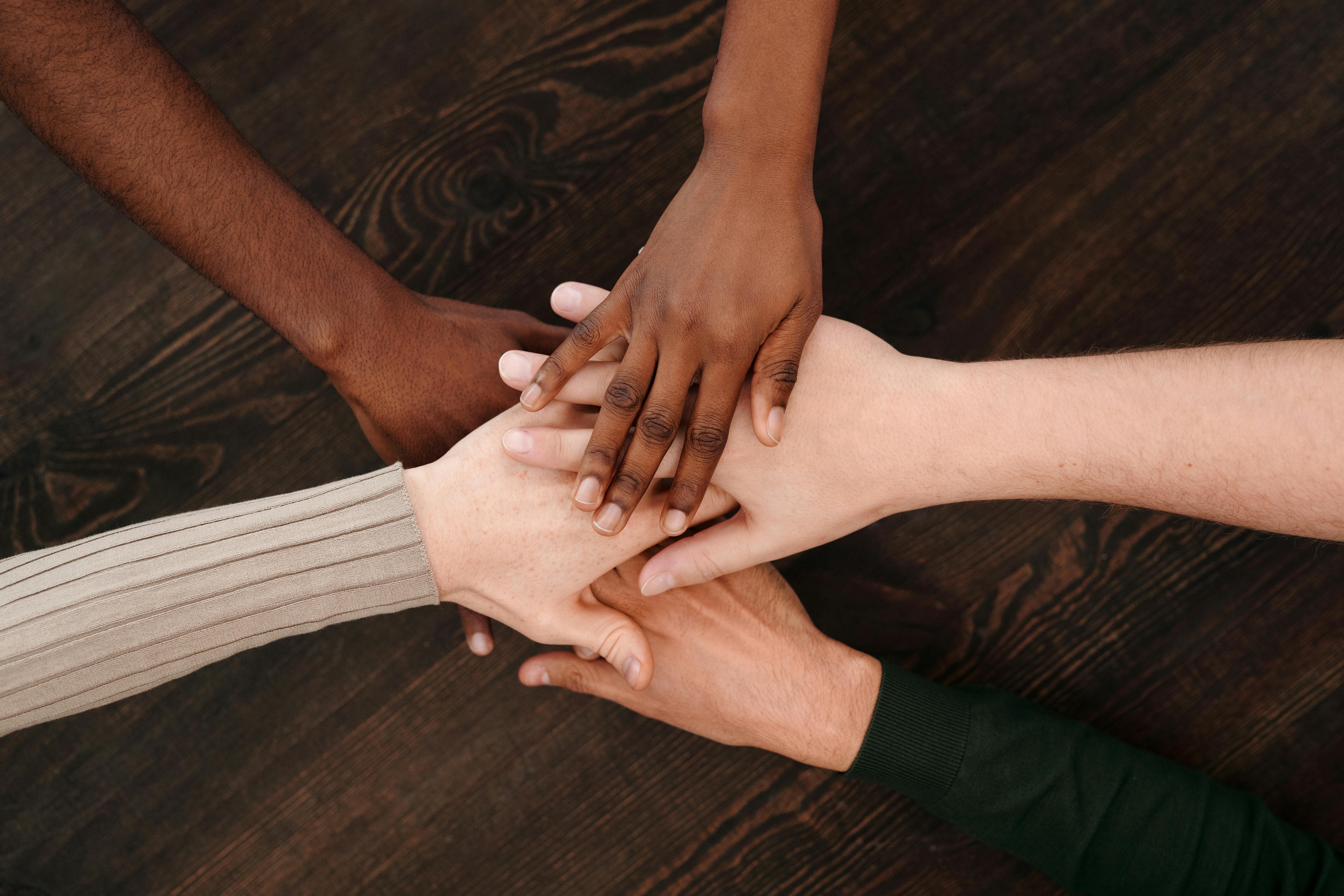 Hands of five people coming together in a circle
